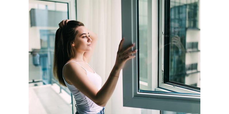 mujer frente a ventana abierta.