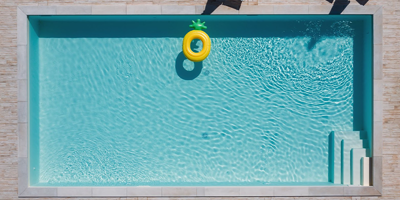 Piscina celeste con inflable flotando y cinco reposeras al costado.