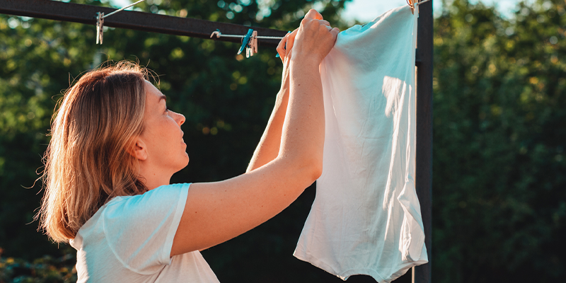 Mujer colgando ropa en una estructura al aire libre.